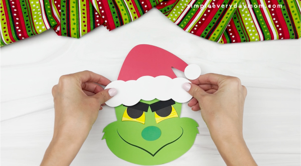 hands gluing hat to Grinch card craft