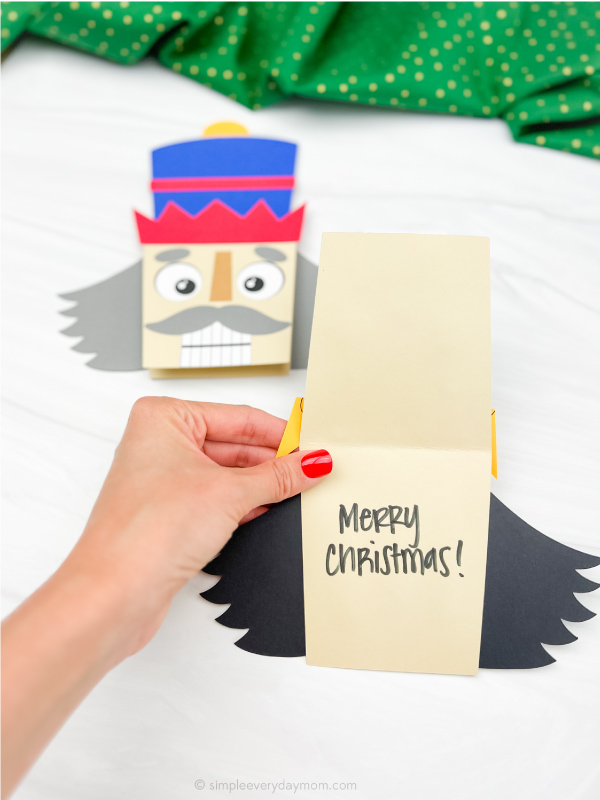 hand holding nutcracker card craft open with a second one in the background