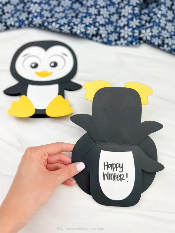 hand holding penguin card craft open with a second one in the background