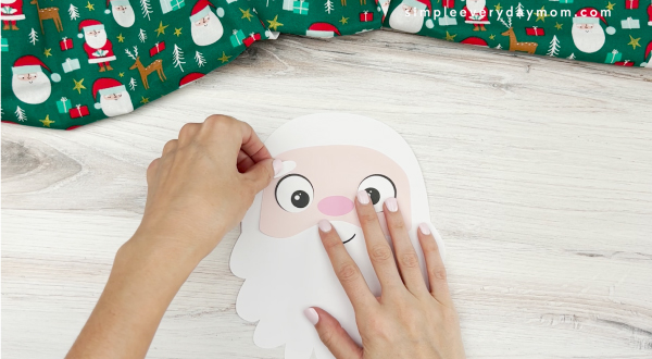 hands placing eyebrows on face of santa name craft