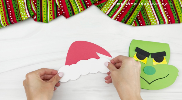hands gluing hat fluff to hat of Grinch card craft