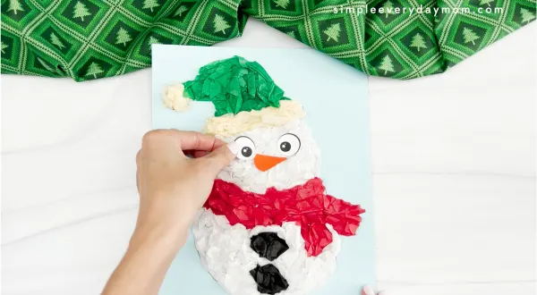 hands gluing eye to tissue paper snowman