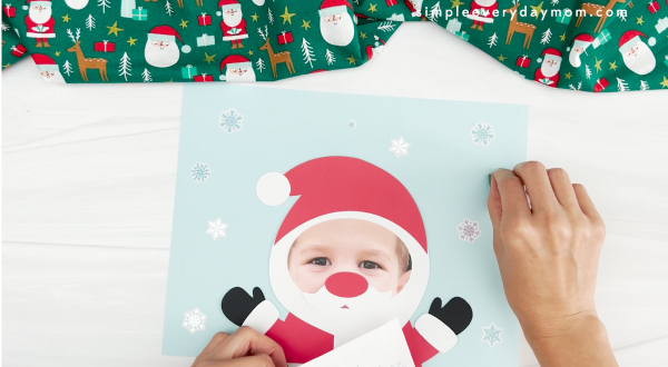 hands placing snowflake stickers onto Santa photo craft