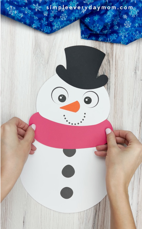 hands gluing scarf to handprint snowman craft