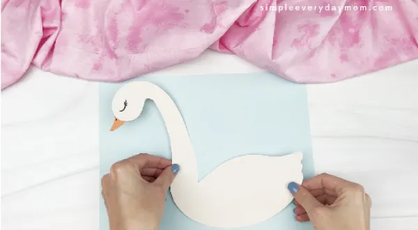 hands gluing swan body to background paper