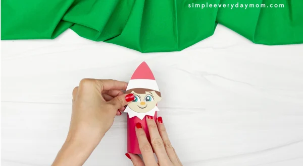 hands placing the finished elf head onto the elf body toilet paper roll