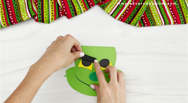 hands gluing eyebrows to Grinch card craft