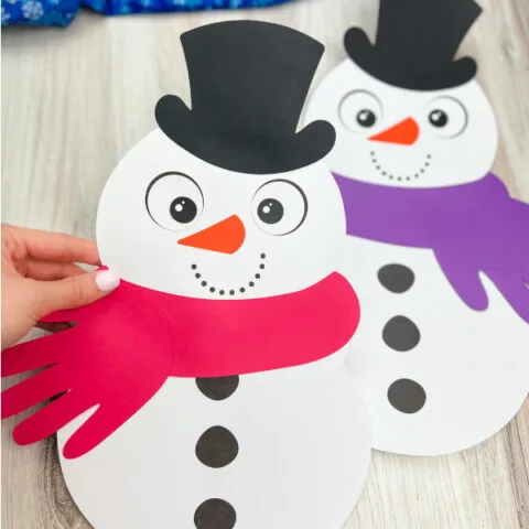 hand holding handprint snowman craft with another one in the background