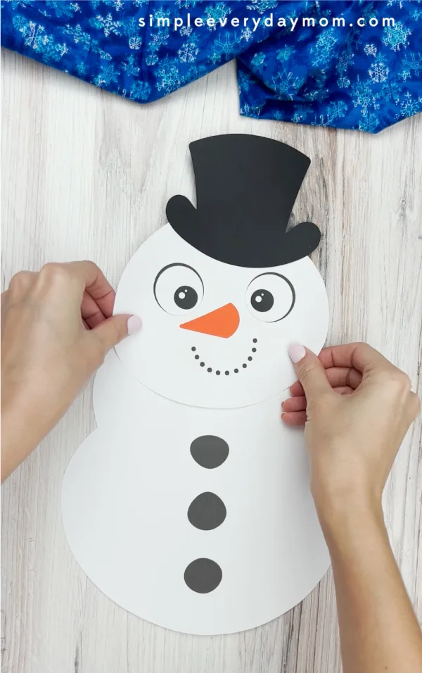 hands gluing head to handprint snowman craft