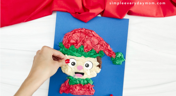 hand is placing eyes on elf tissue paper craft