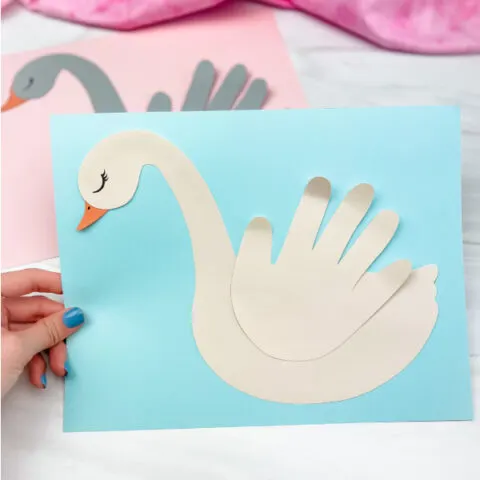 hand holding swan handprint craft with another one in the background
