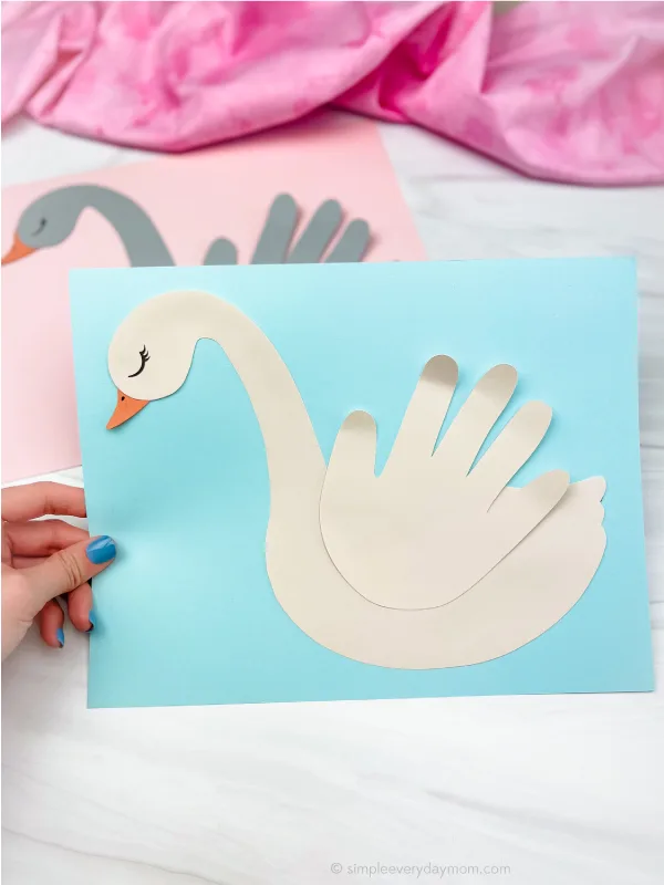 hand holding swan handprint craft with another one in the background
