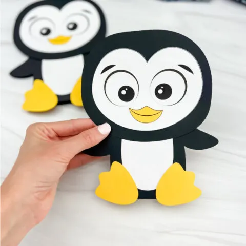 hand holding penguin card craft with a second one in the background