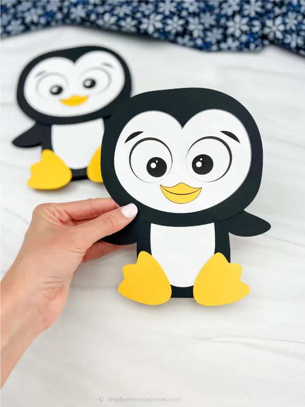 hand holding penguin card craft with a second one in the background