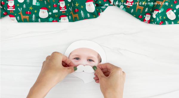hands placing mustache of beard onto face for Santa photo craft