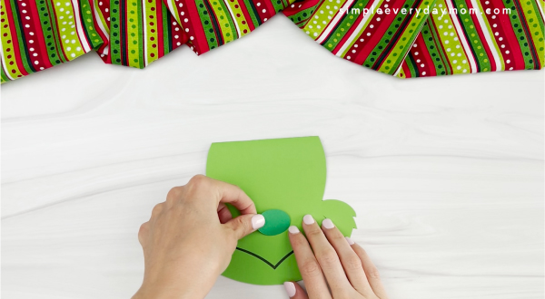 hands gluing nose to Grinch card craft