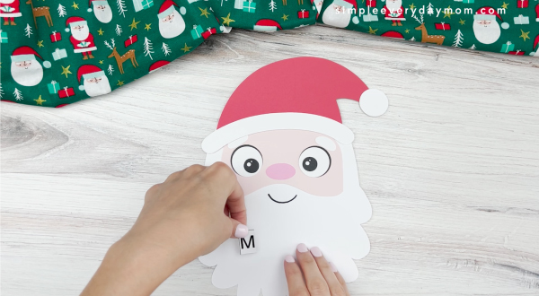 hands placing letters on santa beard displaying where to place letters of name for santa name craft