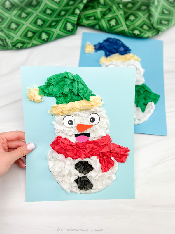 hand holding tissue paper snowman craft with another one in the background