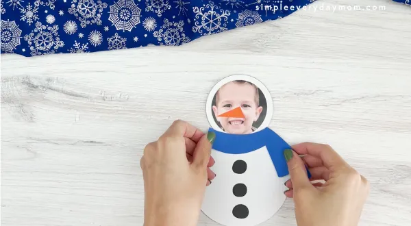 hand placing scarf on to snowman photo craft