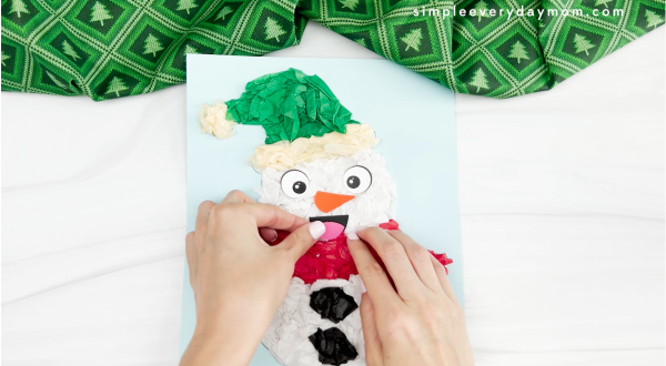 hands gluing tongue to mouth of tissue paper snowman