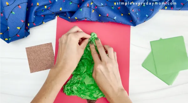 hands assembling green tissue paper onto Christmas tree tissue paper craft