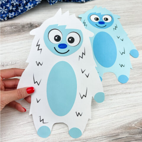 hand holding white abominable snowman craft with a light blue one in the background