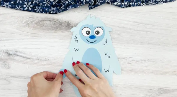 hands gluing end of arm to abominable snowman craft