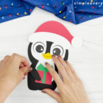 hands placing arms onto body of Christmas penguin craft