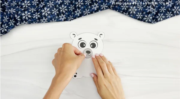 hands assembling snout of polar bear onto face