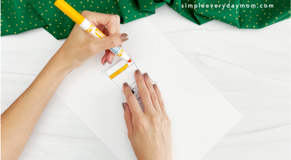 hands coloring with yellow marker onto template for nutcracker toilet paper roll craft