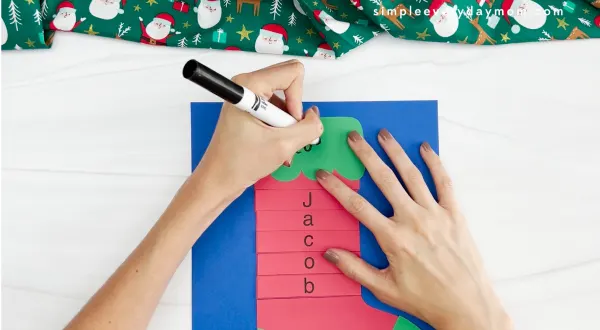 hands using black marker to write on stocking name craft