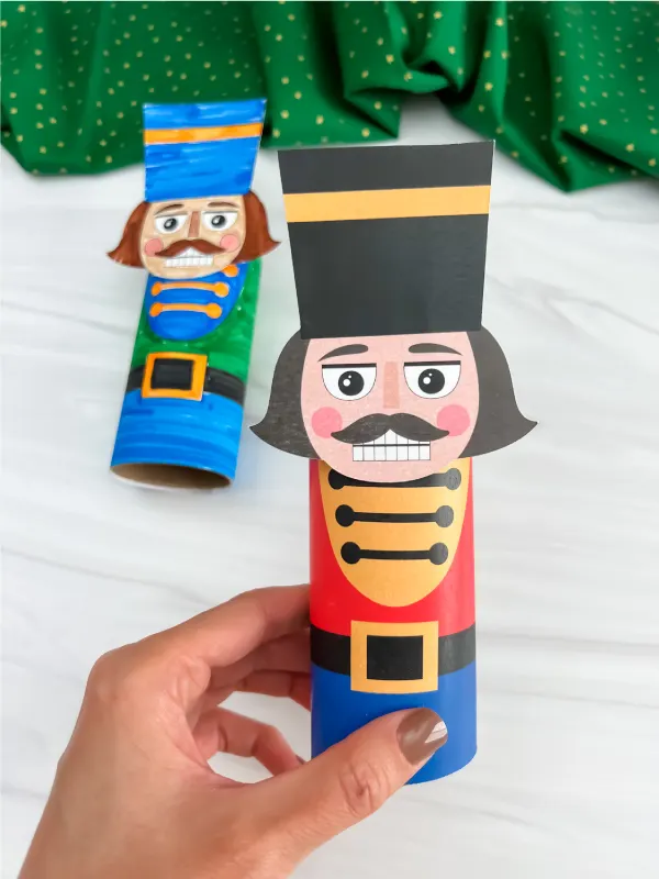 hand holding finished nutcracker toilet paper roll craft with another one in background