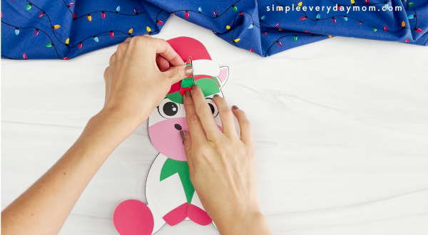 hands placing unicorn onto face of Christmas unicorn craft