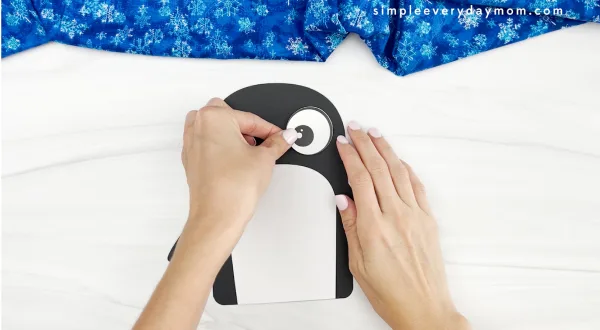 hands gluing eye to name penguin craft