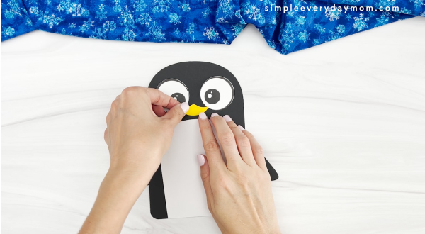 hands gluing beak to name penguin craft