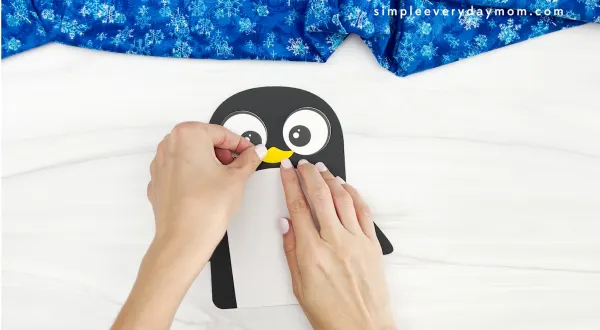hands gluing beak to name penguin craft