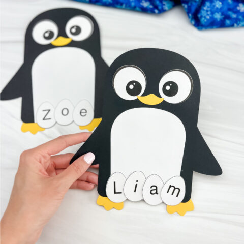 hand holding penguin name craft with a 2nd one in the background