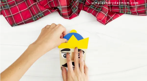 hands placing crown of nutcracker headband craft onto head