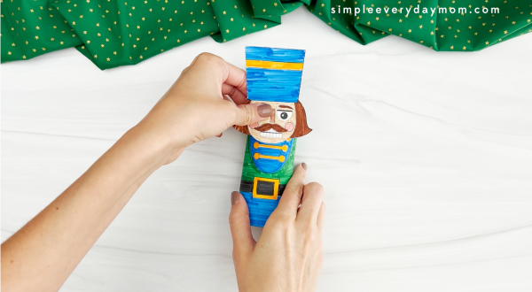 hands placing head onto body of nutcracker toilet paper roll craft