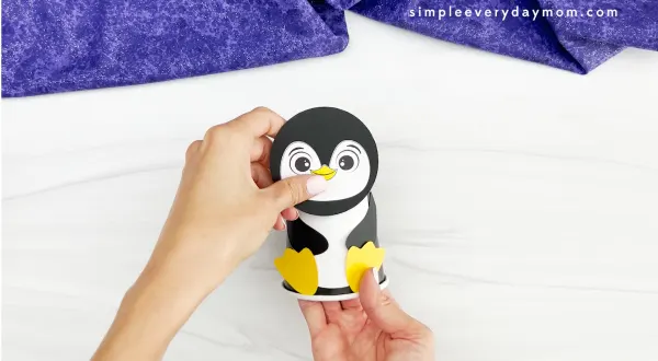 hands assembling head onto body of penguin paper cup craft