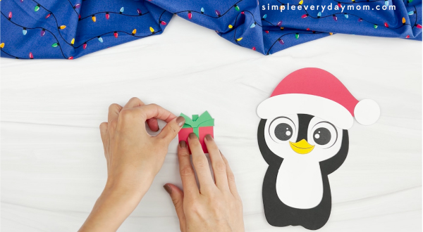 hands assembling Christmas present for Christmas penguin craft