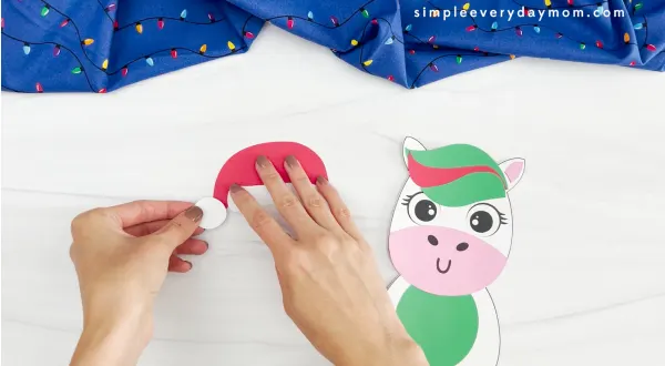 hands assembling Santa cap for Christmas unicorn