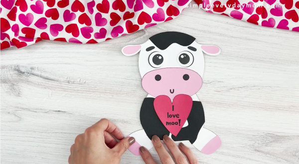 hands assembling legs onto body of cow valentine craft