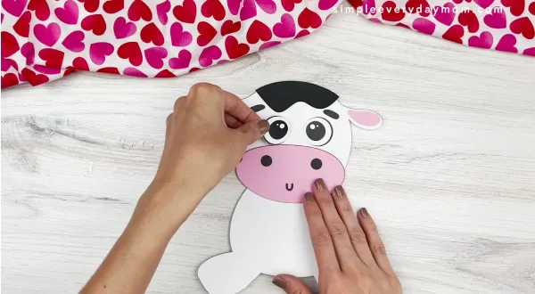 hands placing eyes onto face of cow valentine craft