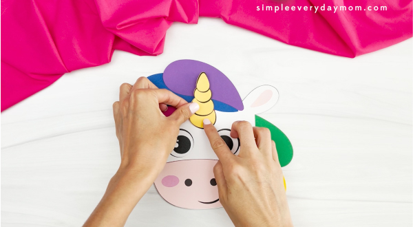 hands gluing unicorn onto head of unicorn rainbow puppet
