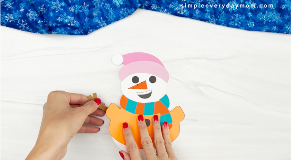 hands placing arms onto body of Sneezy the snowman
