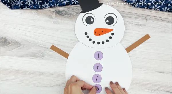 hands placing letters onto body of snowman name craft