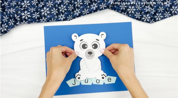 hands gluing finished polar bear onto sheet with name on it
