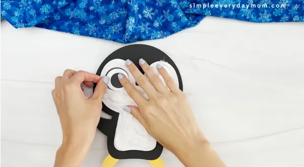 hand gluing the eyes of the puffy penguin craft