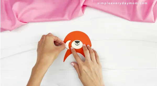 hands gluing parts of face onto red panda